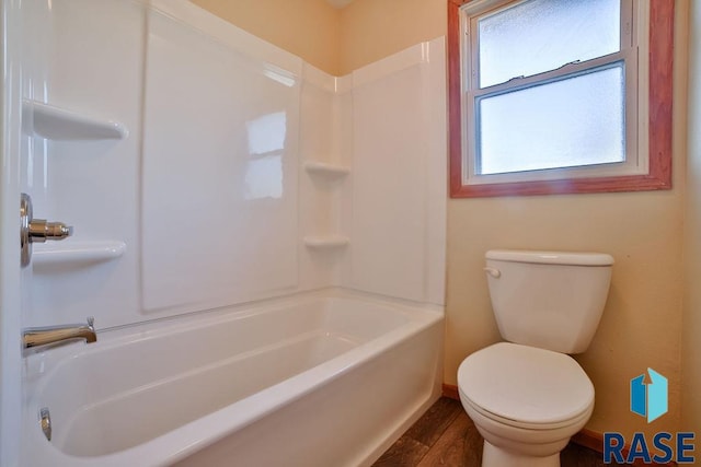 bathroom featuring hardwood / wood-style flooring, shower / washtub combination, and toilet