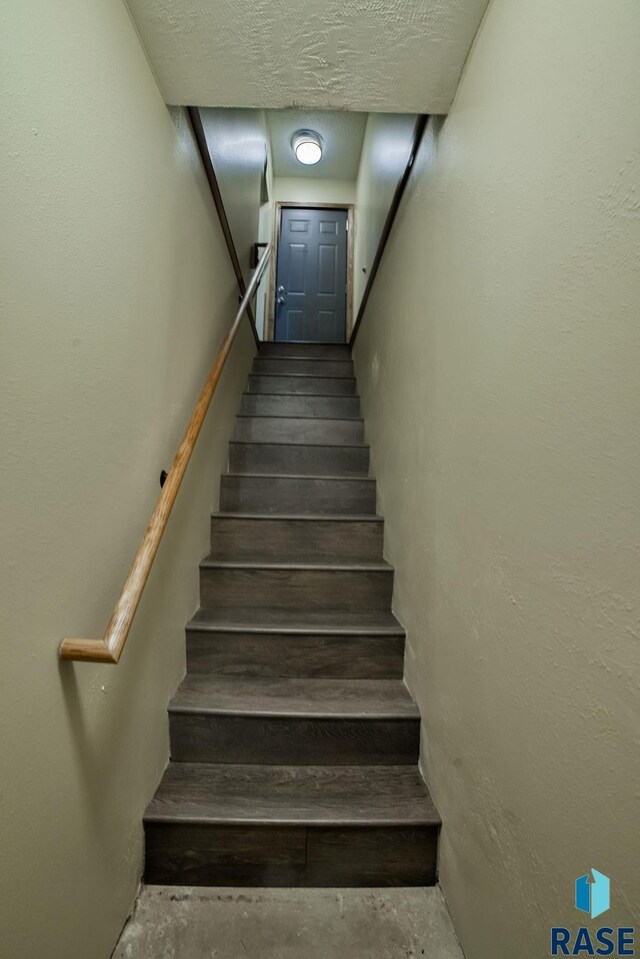 stairs with concrete floors and a textured ceiling