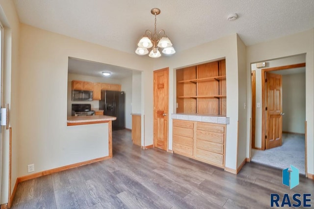 kitchen featuring pendant lighting, range, dark hardwood / wood-style floors, a textured ceiling, and black fridge