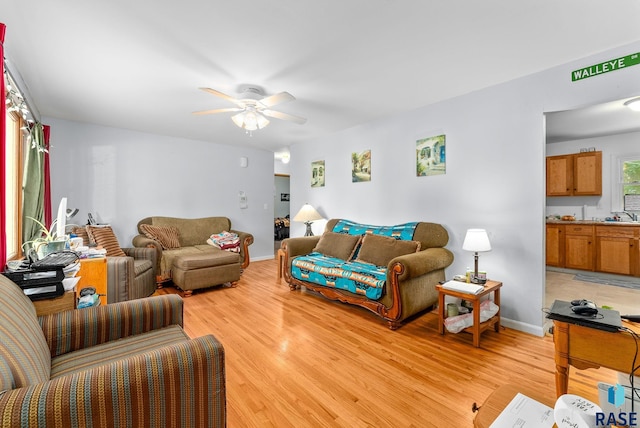 living room featuring ceiling fan, sink, and light wood-type flooring