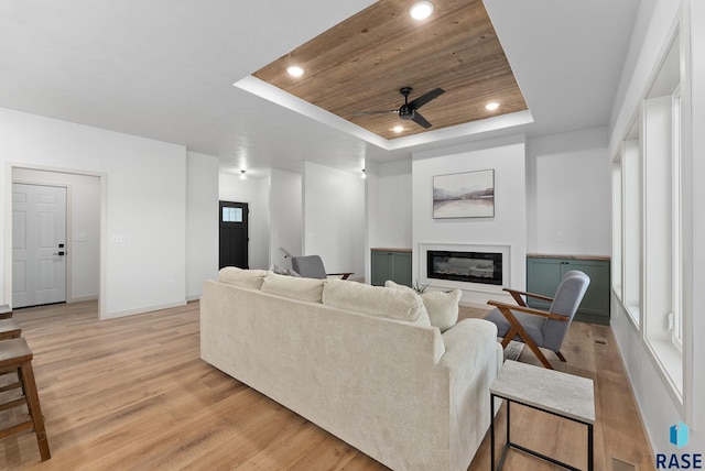 living room featuring a tray ceiling, light hardwood / wood-style flooring, ceiling fan, and wood ceiling