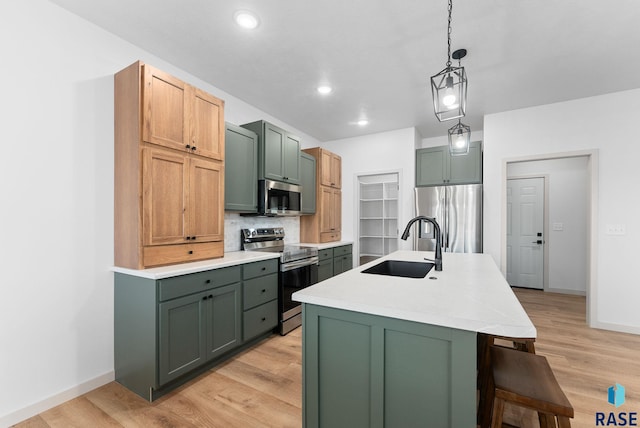 kitchen with light wood-type flooring, stainless steel appliances, and a center island with sink