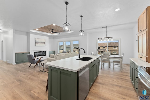 kitchen featuring ceiling fan, sink, light hardwood / wood-style flooring, dishwasher, and an island with sink