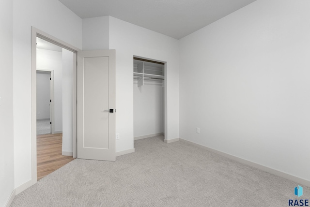 unfurnished bedroom with light colored carpet and a closet