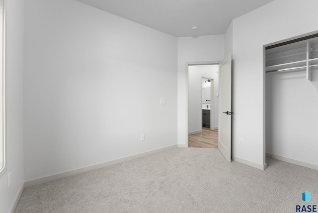 unfurnished bedroom featuring a closet and light colored carpet