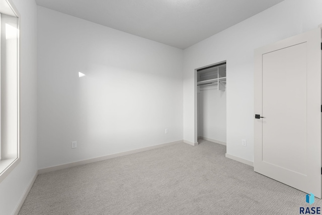 unfurnished bedroom with light carpet and a closet