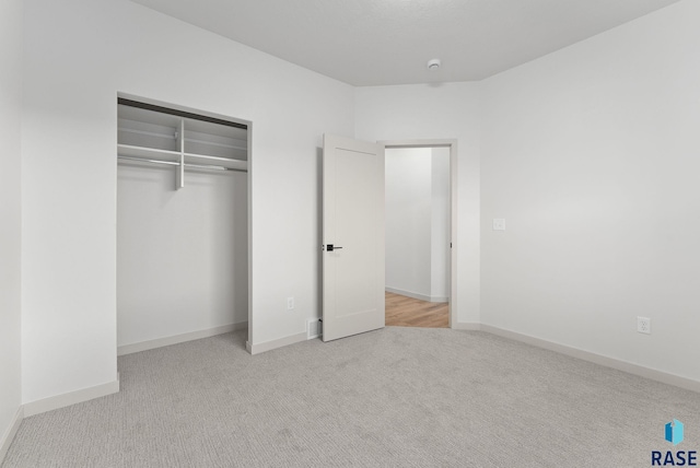 unfurnished bedroom with light colored carpet and a closet