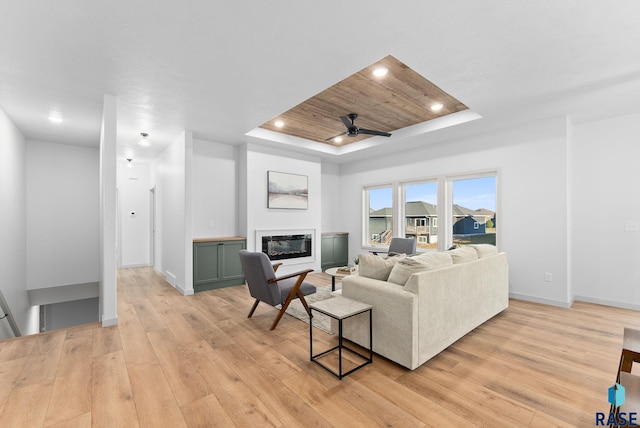 living room featuring light hardwood / wood-style flooring, a raised ceiling, ceiling fan, and wood ceiling