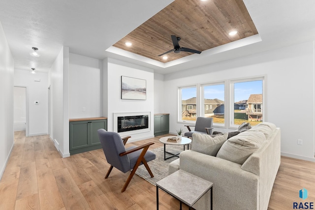 living room with a tray ceiling, ceiling fan, light hardwood / wood-style floors, and wood ceiling