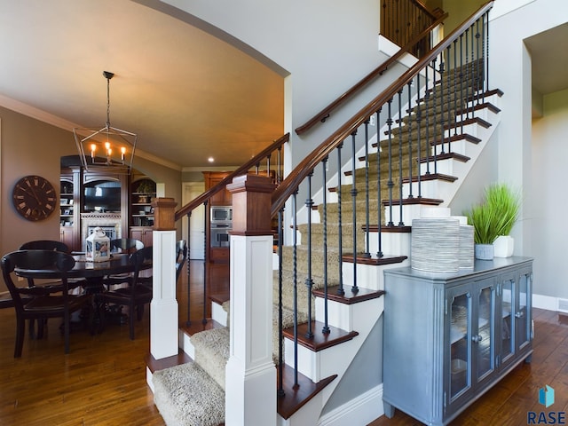 stairs featuring crown molding, hardwood / wood-style floors, and a notable chandelier