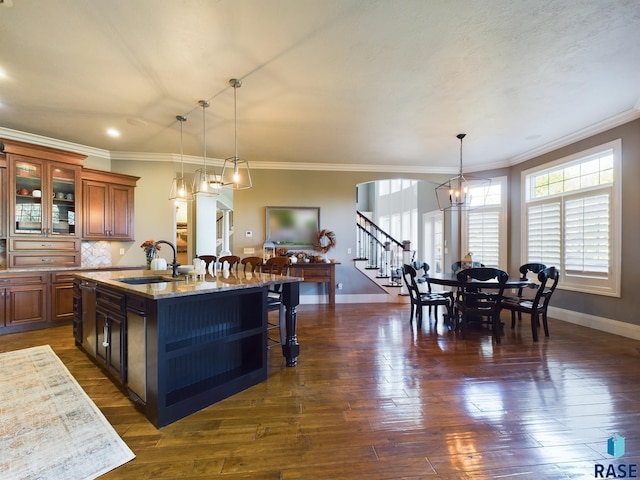 kitchen with light stone countertops, sink, an island with sink, and dark hardwood / wood-style flooring