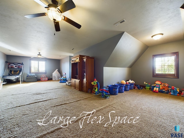 recreation room with lofted ceiling, a textured ceiling, carpet flooring, and ceiling fan