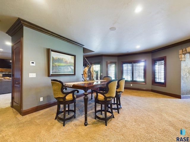 dining area with ornamental molding, light colored carpet, and a textured ceiling