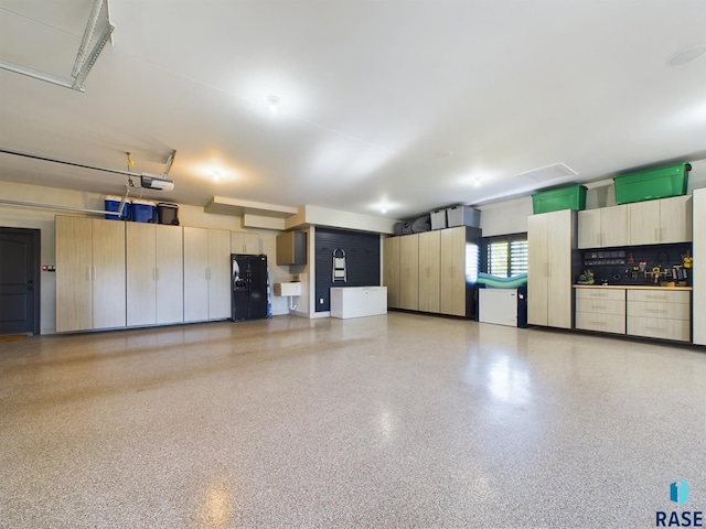 garage featuring black refrigerator with ice dispenser and sink