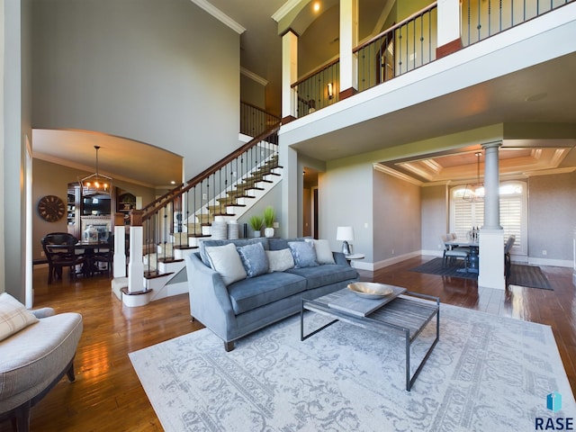 living room featuring a towering ceiling, a notable chandelier, dark hardwood / wood-style floors, and crown molding