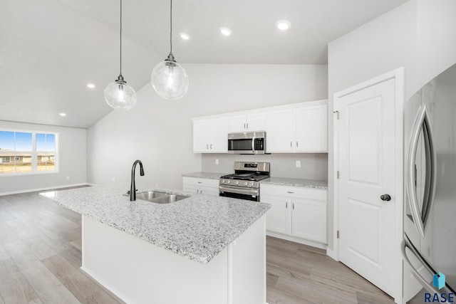 kitchen with white cabinets, hanging light fixtures, appliances with stainless steel finishes, a kitchen island with sink, and sink