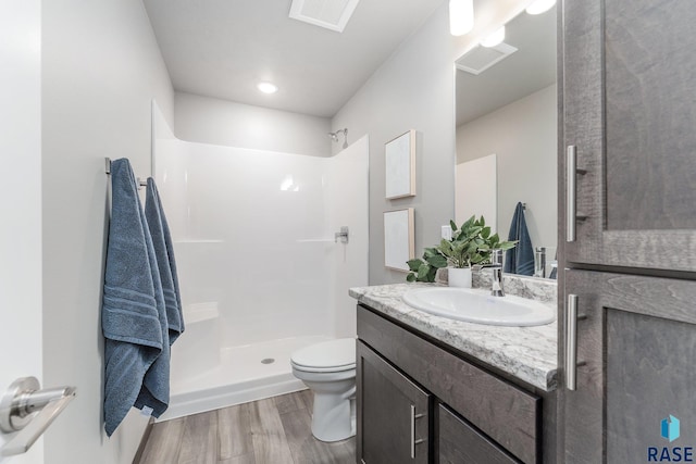 bathroom with hardwood / wood-style flooring, vanity, toilet, and walk in shower