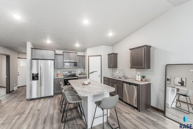 kitchen with a breakfast bar, a center island, sink, light wood-type flooring, and stainless steel appliances