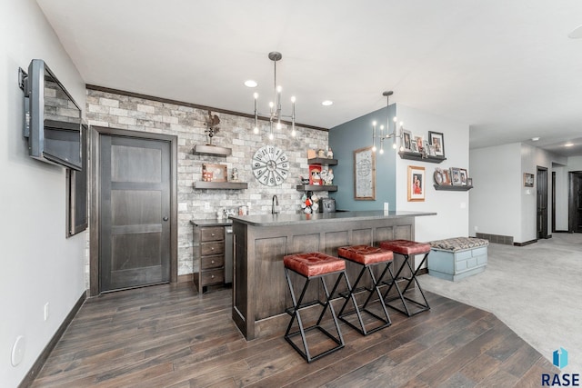 bar with an inviting chandelier, dark wood-type flooring, and hanging light fixtures