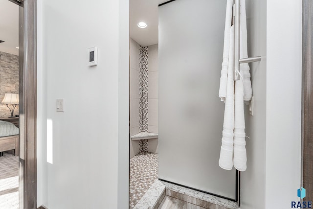 bathroom with a tile shower and hardwood / wood-style floors