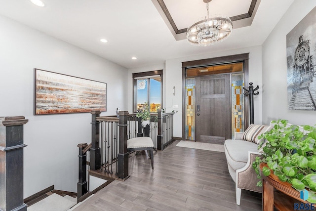 entrance foyer featuring an inviting chandelier, hardwood / wood-style flooring, and a tray ceiling