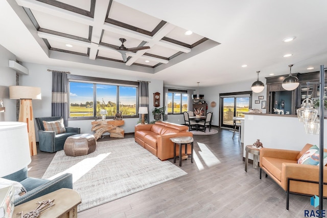 living room featuring beam ceiling, coffered ceiling, light wood-type flooring, and ceiling fan