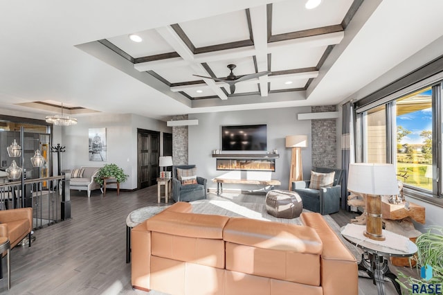 living room featuring hardwood / wood-style flooring, beamed ceiling, ceiling fan with notable chandelier, a fireplace, and coffered ceiling