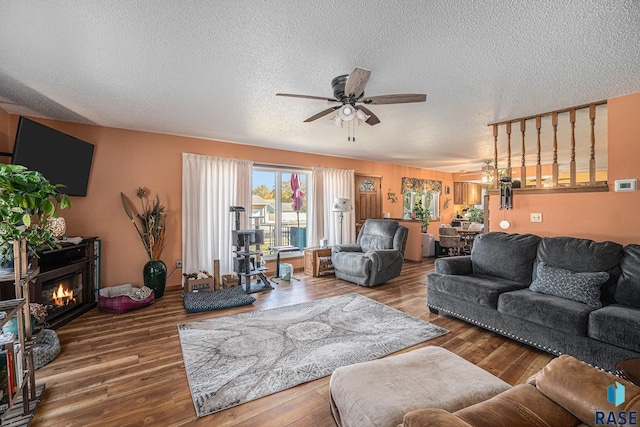 living room featuring a textured ceiling, hardwood / wood-style flooring, and ceiling fan