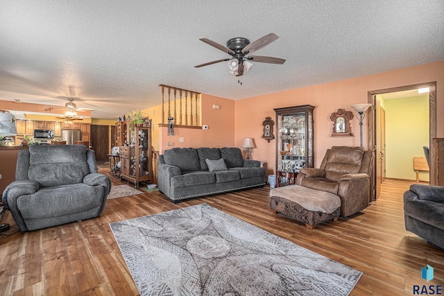 living room with ceiling fan, hardwood / wood-style flooring, and a textured ceiling