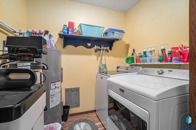 laundry room featuring washer and clothes dryer, electric water heater, and light wood-type flooring