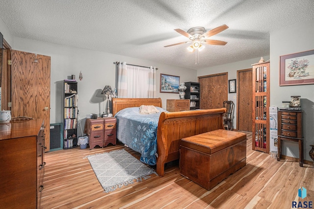 bedroom featuring light hardwood / wood-style floors, a textured ceiling, and ceiling fan