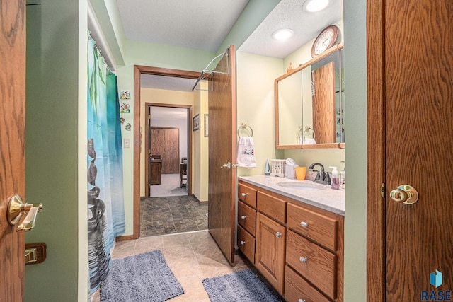 bathroom featuring vanity, a textured ceiling, walk in shower, and tile patterned floors