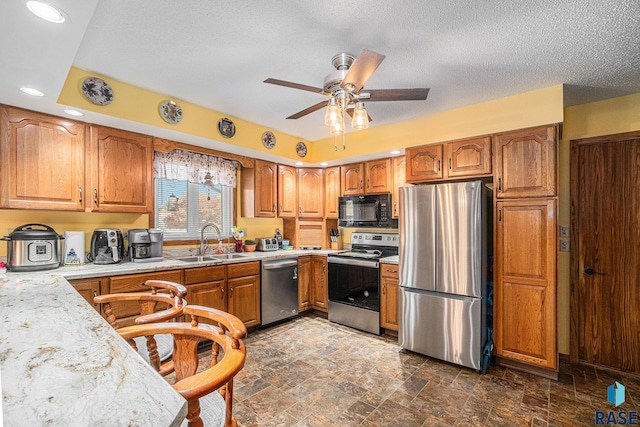 kitchen with ceiling fan, stainless steel appliances, a textured ceiling, and sink