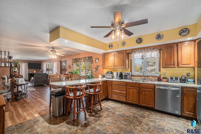 kitchen featuring dark wood-type flooring, sink, stainless steel dishwasher, a textured ceiling, and ceiling fan