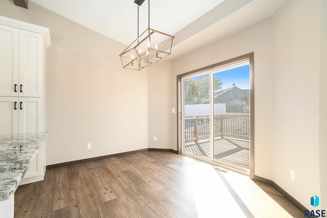 unfurnished dining area with hardwood / wood-style flooring and a notable chandelier