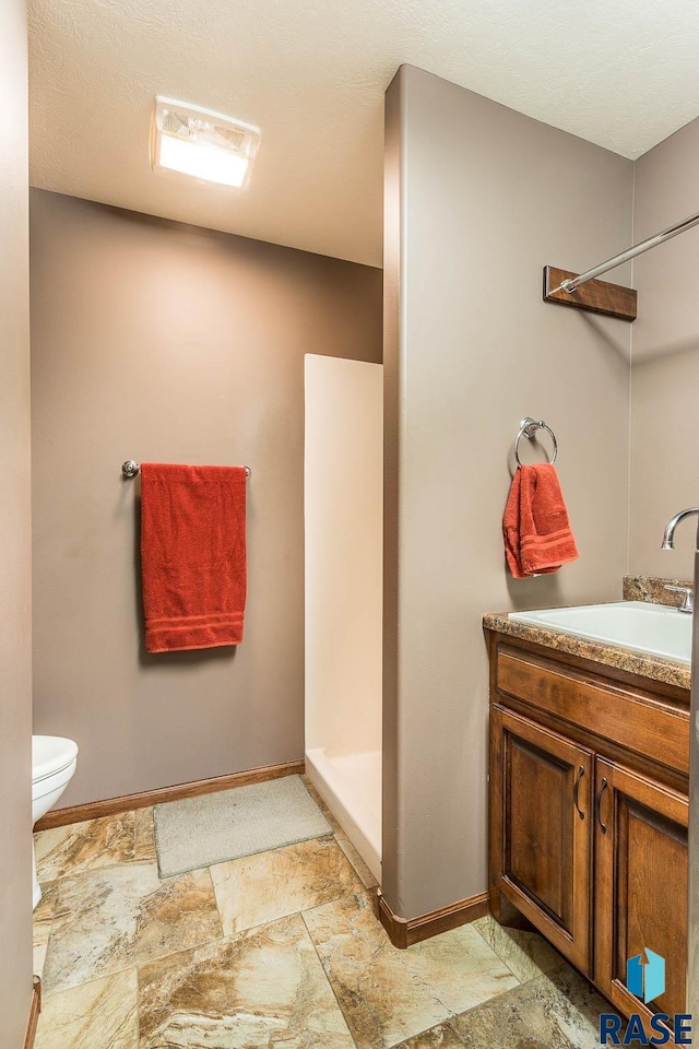 bathroom with vanity, a shower, and toilet