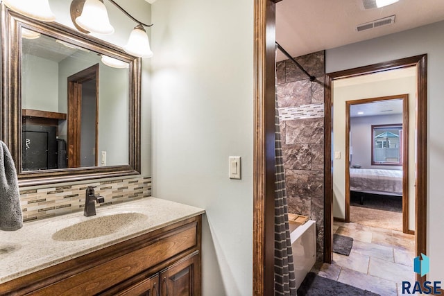 bathroom featuring vanity, decorative backsplash, and tiled shower / bath