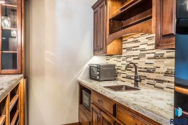 kitchen with built in microwave, sink, decorative backsplash, and light stone counters