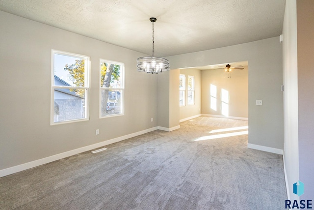 spare room featuring carpet, a textured ceiling, and ceiling fan with notable chandelier