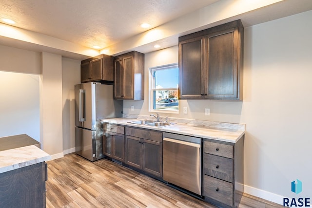 kitchen featuring sink, appliances with stainless steel finishes, light hardwood / wood-style flooring, and dark brown cabinets