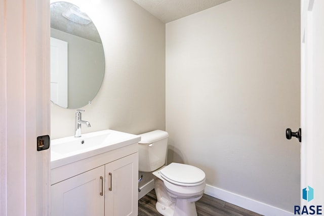 bathroom featuring vanity, a textured ceiling, wood-type flooring, and toilet