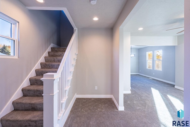 stairs featuring carpet and a textured ceiling