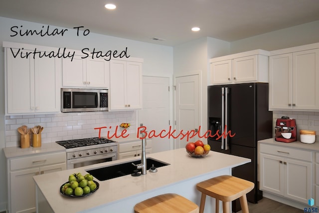 kitchen featuring white cabinets, stainless steel appliances, and a center island with sink