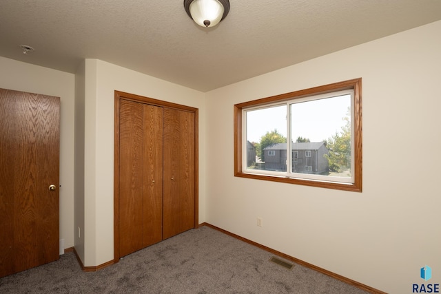 unfurnished bedroom with light colored carpet, a textured ceiling, and a closet