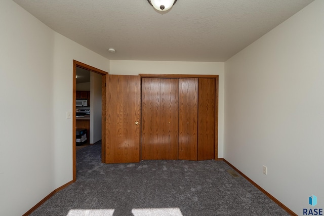 unfurnished bedroom featuring dark colored carpet, a closet, and a textured ceiling