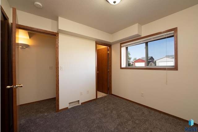 unfurnished bedroom featuring a closet and dark carpet