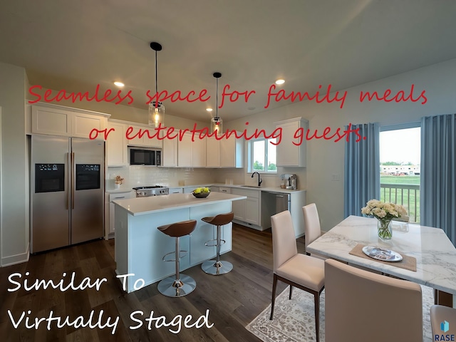 kitchen with appliances with stainless steel finishes, a center island, white cabinetry, a healthy amount of sunlight, and hanging light fixtures