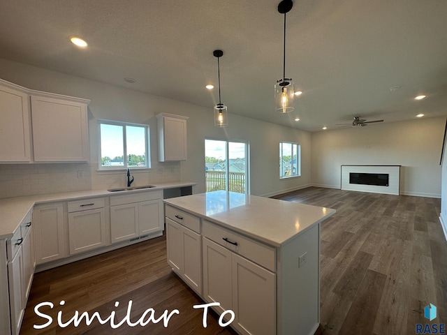 kitchen featuring white cabinets, a kitchen island, sink, pendant lighting, and dark hardwood / wood-style floors