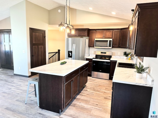 kitchen with appliances with stainless steel finishes, a textured ceiling, sink, light hardwood / wood-style flooring, and a center island