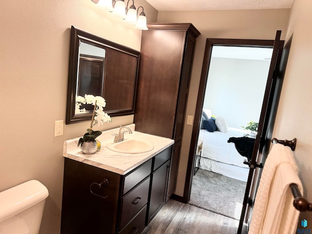 bathroom with hardwood / wood-style floors, vanity, and toilet